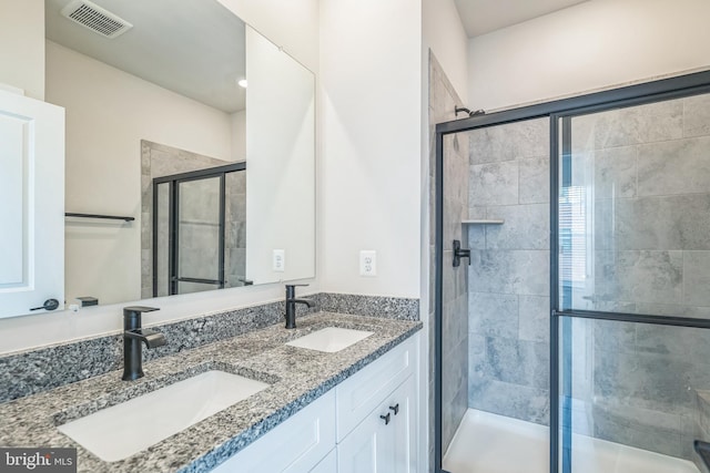full bath featuring visible vents, a sink, double vanity, and a shower stall