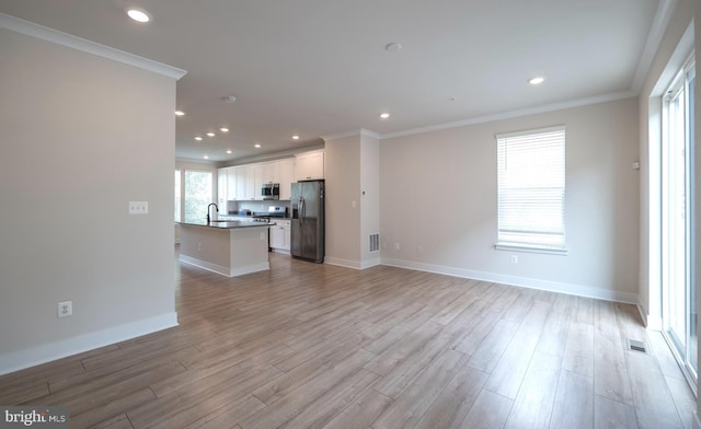 unfurnished living room with light hardwood / wood-style flooring, crown molding, and sink