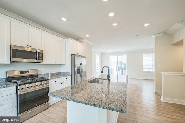 kitchen featuring ornamental molding, a sink, light wood-type flooring, and appliances with stainless steel finishes