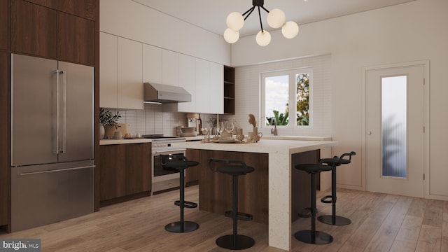 kitchen with pendant lighting, exhaust hood, stainless steel appliances, a breakfast bar area, and light hardwood / wood-style floors