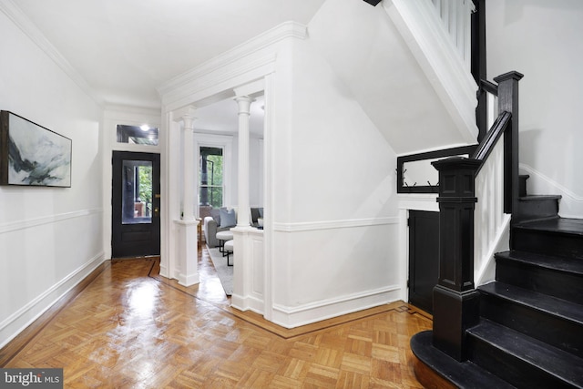 entrance foyer with crown molding, decorative columns, and light parquet flooring