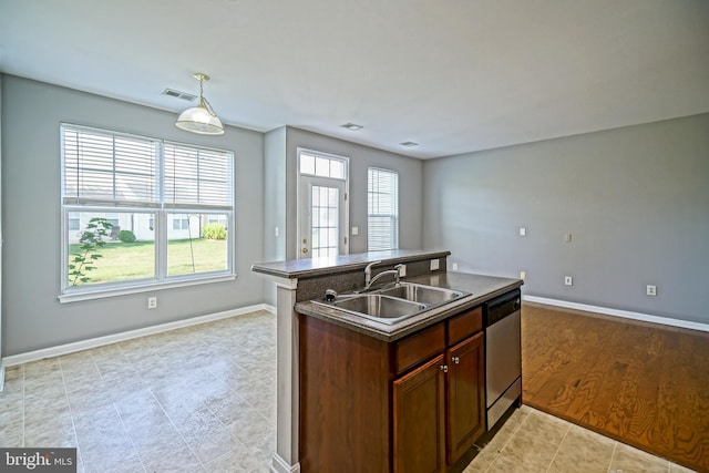 kitchen featuring light wood-type flooring, a center island with sink, sink, dishwasher, and hanging light fixtures