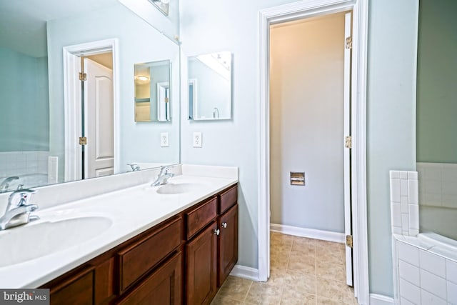 bathroom featuring tile patterned flooring, tiled bath, and vanity