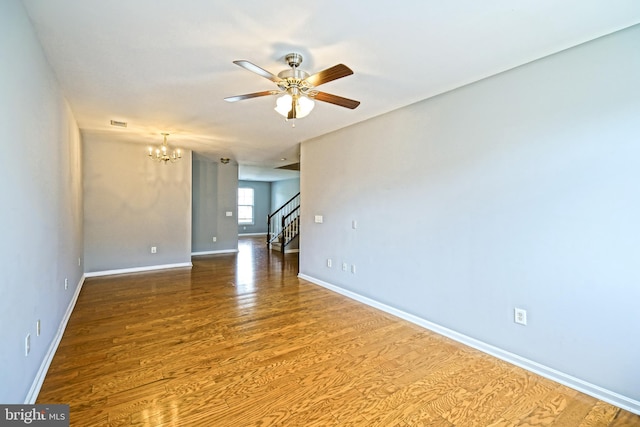 spare room with wood-type flooring and ceiling fan with notable chandelier