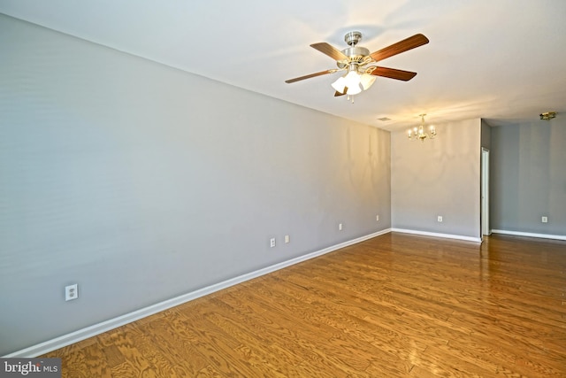 unfurnished room featuring ceiling fan with notable chandelier and hardwood / wood-style flooring