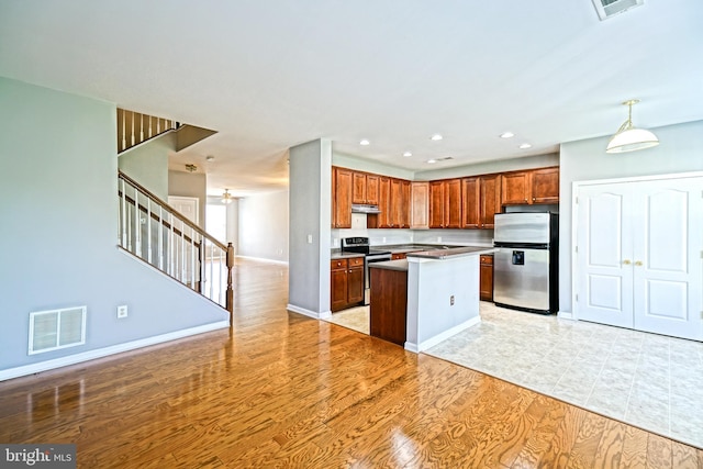 kitchen with decorative light fixtures, appliances with stainless steel finishes, light wood-type flooring, and a center island