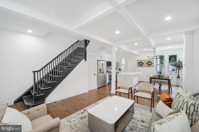 living room with coffered ceiling, beamed ceiling, light wood-type flooring, and an inviting chandelier