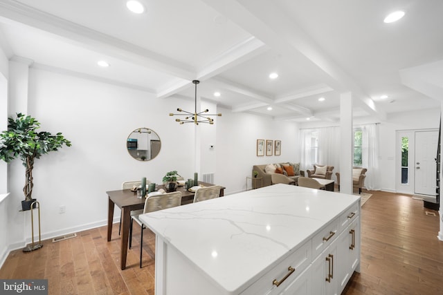 kitchen featuring light wood-type flooring, light stone counters, a center island, white cabinets, and beam ceiling