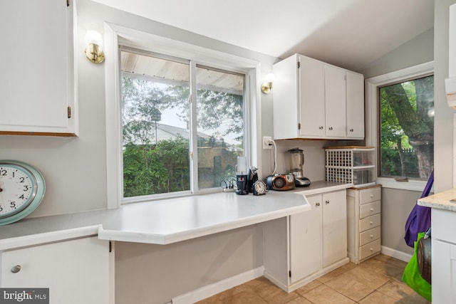 kitchen featuring white cabinets, vaulted ceiling, and light tile patterned floors