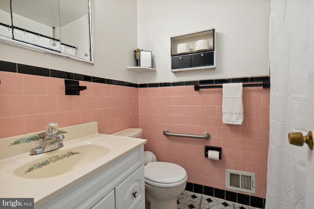 bathroom featuring vanity, tile walls, and toilet