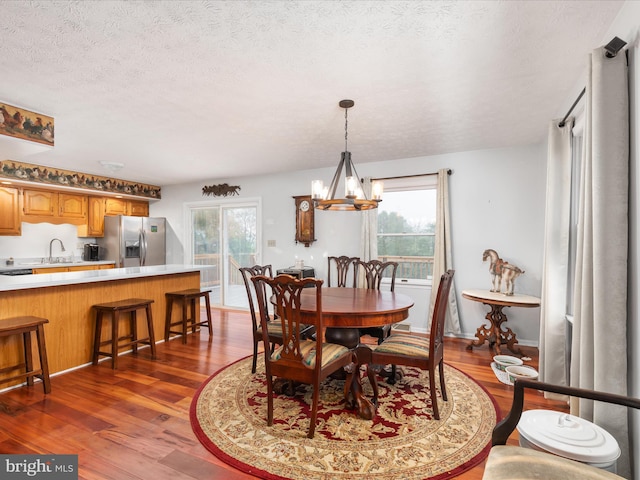 dining room featuring a textured ceiling, a healthy amount of sunlight, dark hardwood / wood-style floors, and a notable chandelier