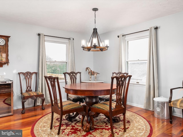 dining room with wood-type flooring and an inviting chandelier