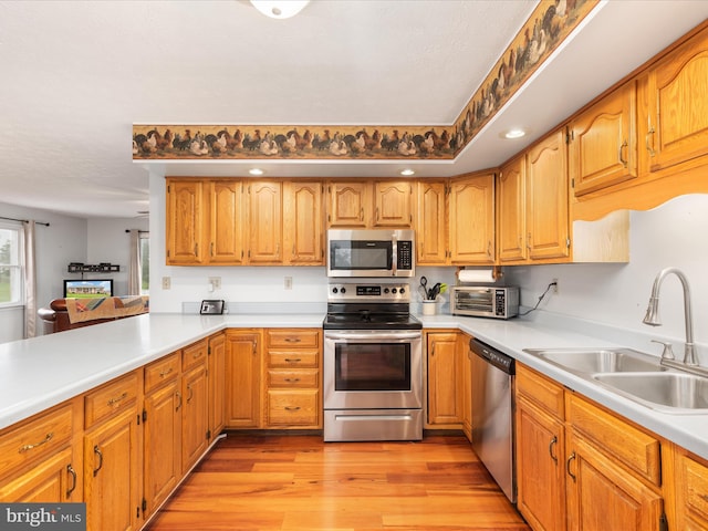 kitchen featuring light hardwood / wood-style floors, sink, stainless steel appliances, and kitchen peninsula