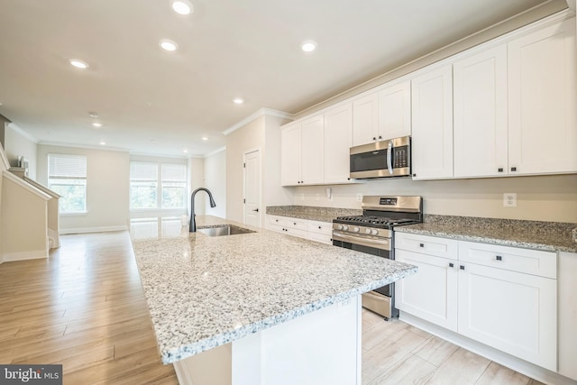 kitchen featuring white cabinets, a center island with sink, appliances with stainless steel finishes, and sink