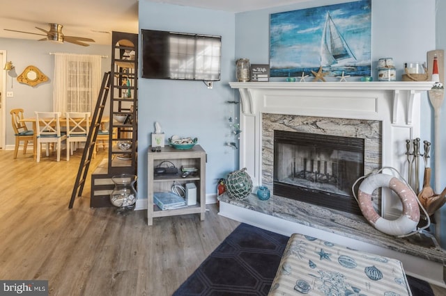 living area with ceiling fan, hardwood / wood-style floors, and a fireplace