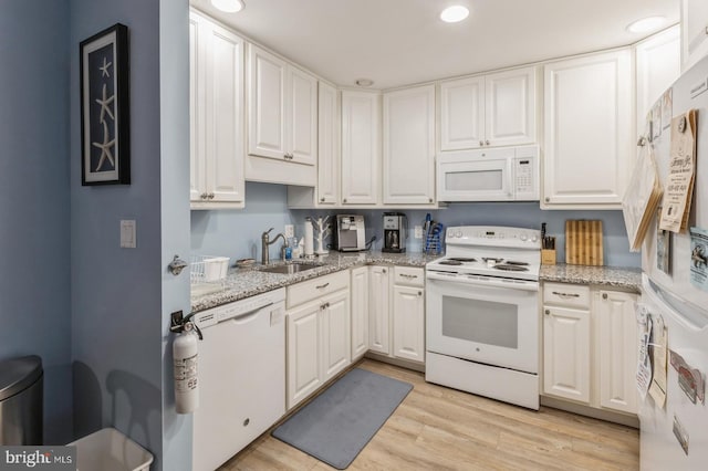 kitchen with sink, white appliances, light stone counters, white cabinets, and light wood-type flooring