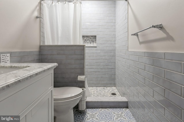 bathroom featuring toilet, tile walls, vanity, curtained shower, and tile patterned flooring