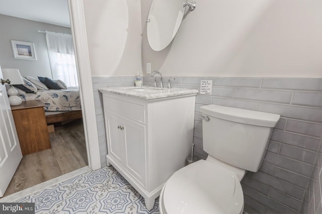 bathroom with hardwood / wood-style flooring, vanity, tile walls, and toilet