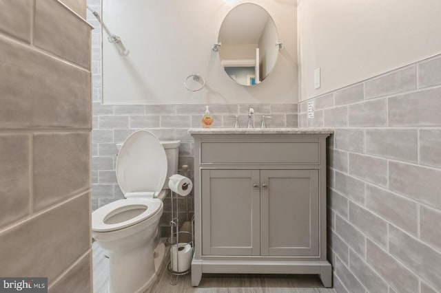 bathroom featuring tile walls, vanity, and toilet