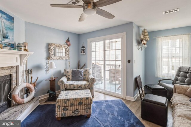 living area featuring ceiling fan, a premium fireplace, and light wood-type flooring