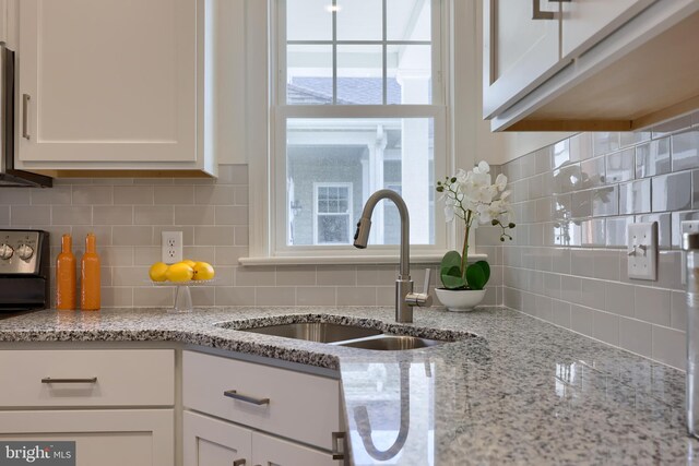 kitchen featuring backsplash, plenty of natural light, sink, and white cabinetry