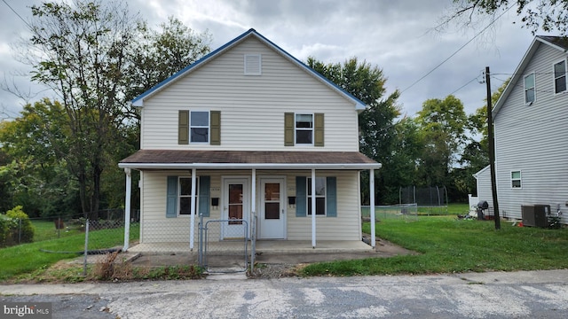 view of front of property with a front lawn, cooling unit, a trampoline, and covered porch