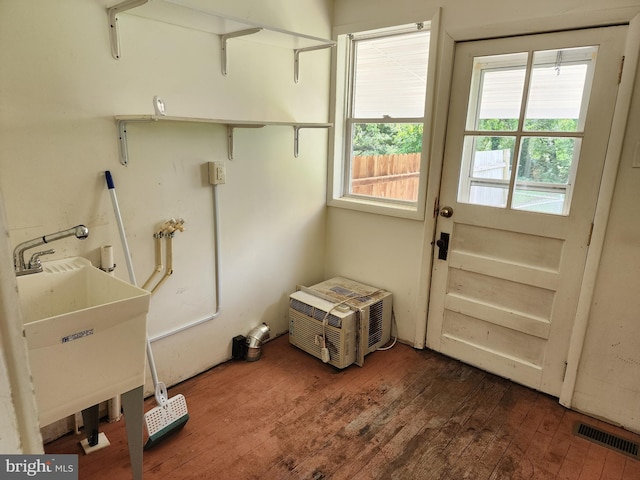 clothes washing area with sink, dark hardwood / wood-style flooring, and an AC wall unit