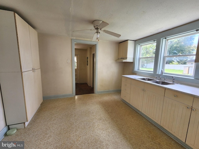 kitchen with a textured ceiling, light brown cabinets, ceiling fan, and sink