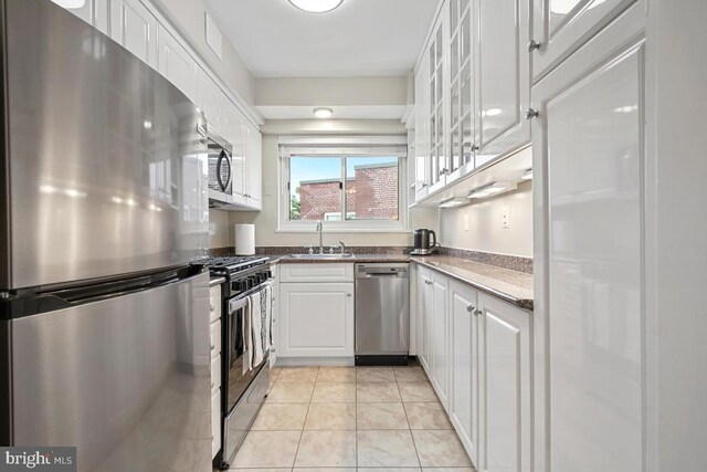 kitchen with white cabinets, appliances with stainless steel finishes, light tile patterned floors, and sink