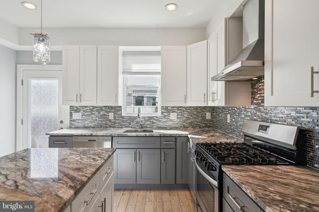 kitchen featuring appliances with stainless steel finishes, gray cabinetry, wall chimney exhaust hood, and sink