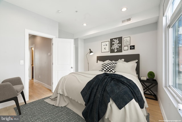 bedroom with multiple windows and light hardwood / wood-style flooring