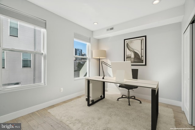 home office with light hardwood / wood-style flooring