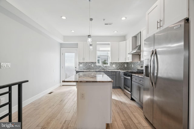 kitchen featuring a kitchen island, light stone counters, hanging light fixtures, white cabinetry, and appliances with stainless steel finishes