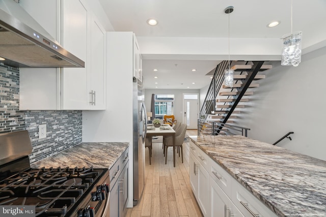 kitchen with wall chimney range hood, white cabinets, appliances with stainless steel finishes, and light hardwood / wood-style floors