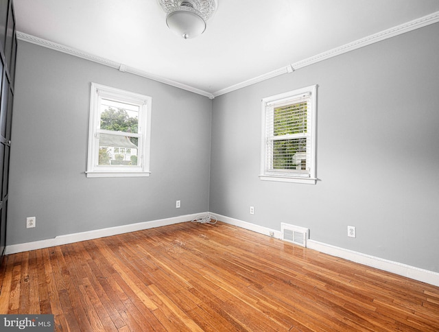 empty room with wood-type flooring and crown molding