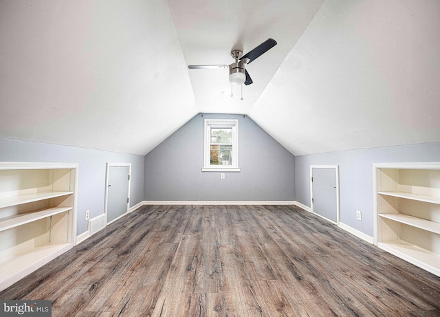 additional living space with vaulted ceiling, dark hardwood / wood-style floors, built in features, and ceiling fan