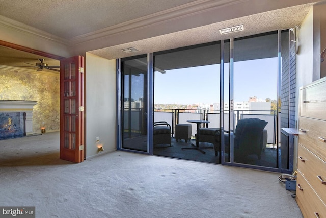 interior space with ceiling fan, floor to ceiling windows, carpet flooring, ornamental molding, and a textured ceiling