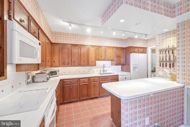 kitchen with sink, white appliances, light tile patterned floors, backsplash, and a textured ceiling