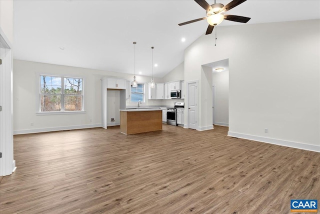 unfurnished living room with ceiling fan, light wood-type flooring, sink, and high vaulted ceiling