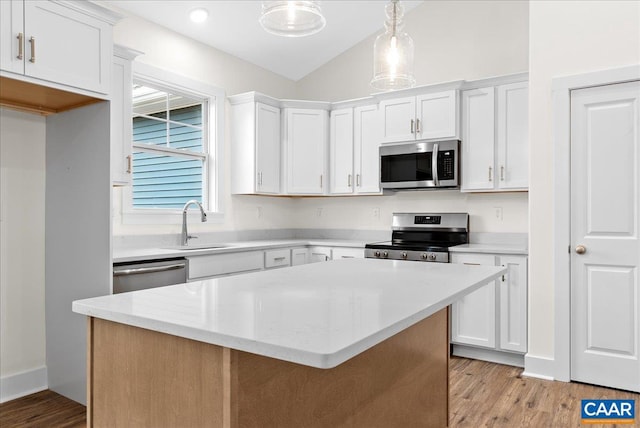 kitchen with a kitchen island, pendant lighting, stainless steel appliances, and white cabinetry