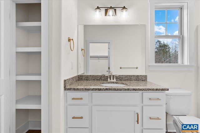 bathroom featuring toilet, built in features, and vanity