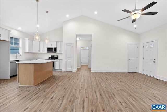 kitchen with ceiling fan, stainless steel appliances, a kitchen island, pendant lighting, and white cabinets