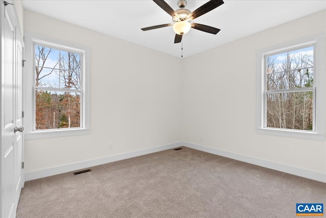 carpeted spare room with ceiling fan and plenty of natural light