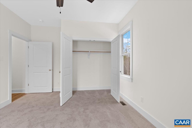 unfurnished bedroom featuring ceiling fan, a closet, and light carpet