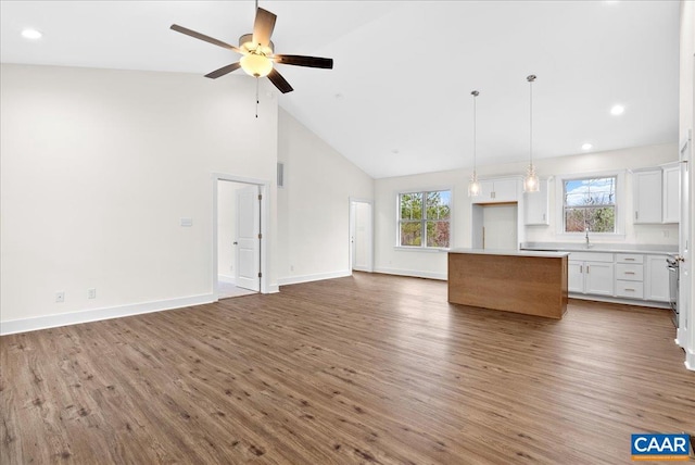 interior space with ceiling fan, a kitchen island, white cabinetry, hardwood / wood-style flooring, and high vaulted ceiling