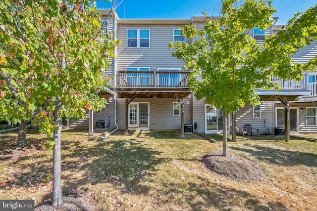 rear view of property with a wooden deck, central AC unit, and a yard