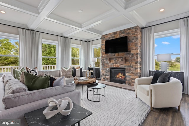 living room with ornamental molding, beam ceiling, a stone fireplace, coffered ceiling, and dark hardwood / wood-style floors