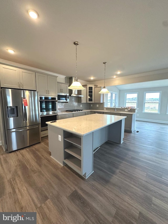 kitchen featuring appliances with stainless steel finishes, hanging light fixtures, light stone countertops, a center island, and dark hardwood / wood-style floors