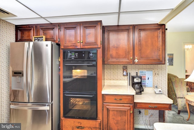 kitchen featuring stainless steel fridge, light countertops, and wallpapered walls