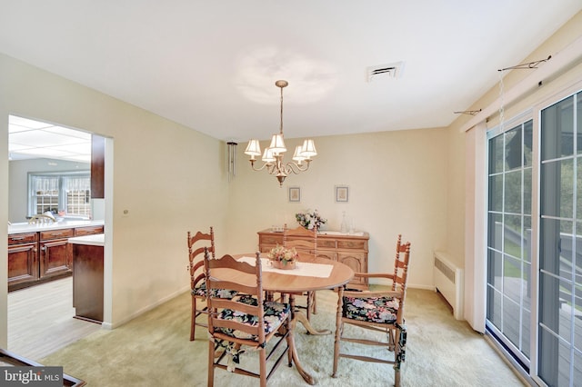 dining room with radiator heating unit, light colored carpet, a chandelier, and baseboards